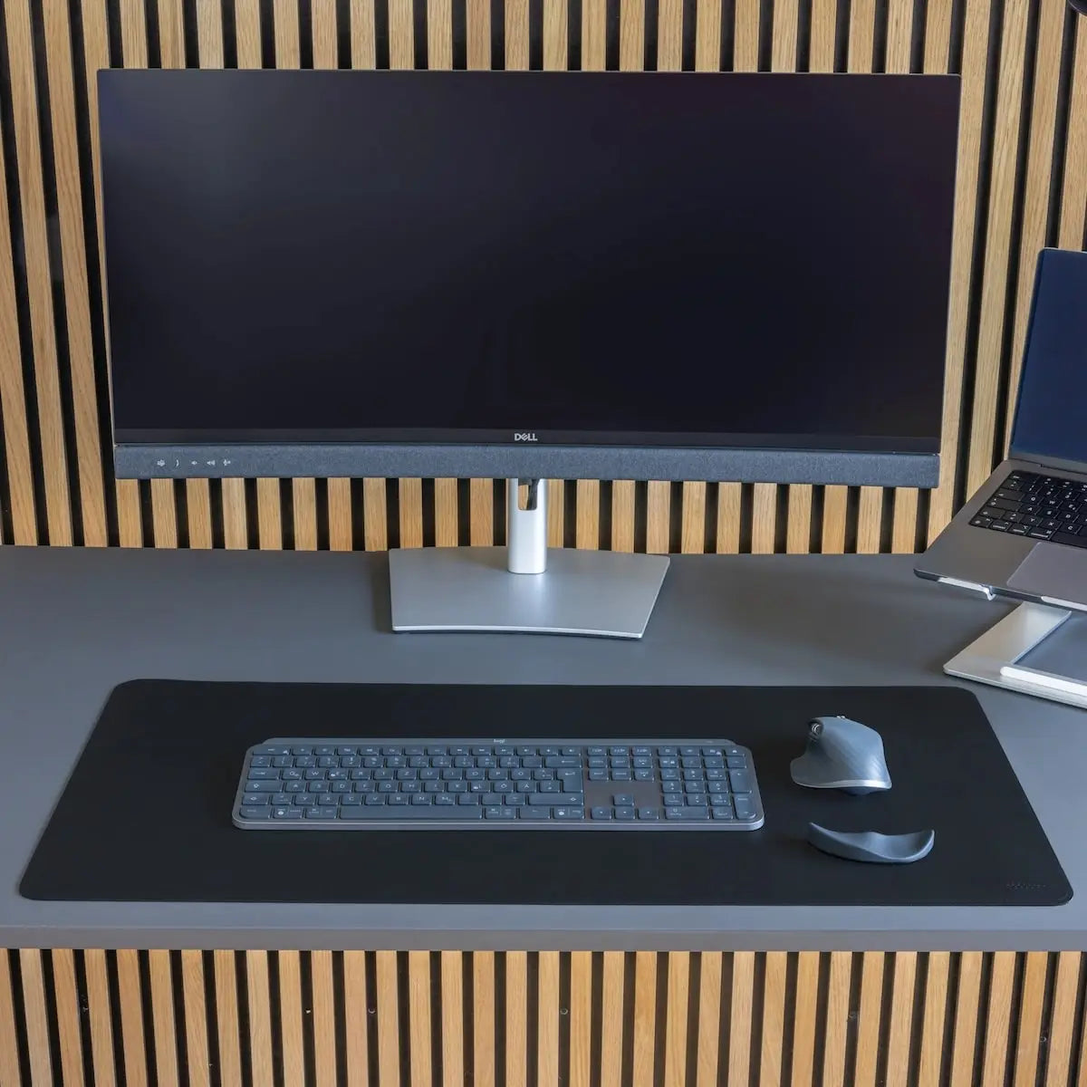 Modernes Schreibtisch-Setup mit einem Dell-Monitor, einer schwarzen MATDESK Schreibtischunterlage, einer Tastatur und Maus. Die elegante Schreibtischunterlage bietet eine rutschfeste, stilvolle Arbeitsfläche für eine aufgeräumte und professionelle Arbeitsumgebung.